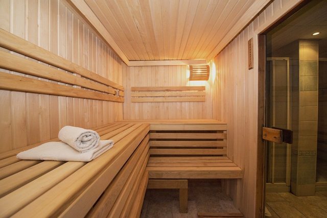 Timber-lined infrared sauna with tiered bench seating and a rolled towel