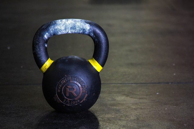 A dark blue kettlebell standing on a timber training floor