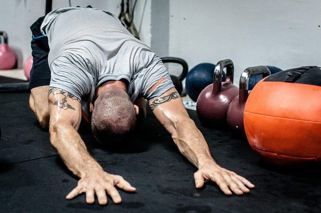 A member holding a push up position beside kettlebells and a medicine ball