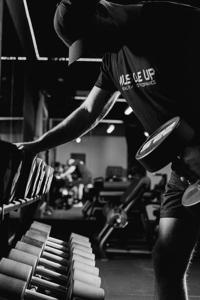 A member lifting a dumbbell from the rack on the gym floor